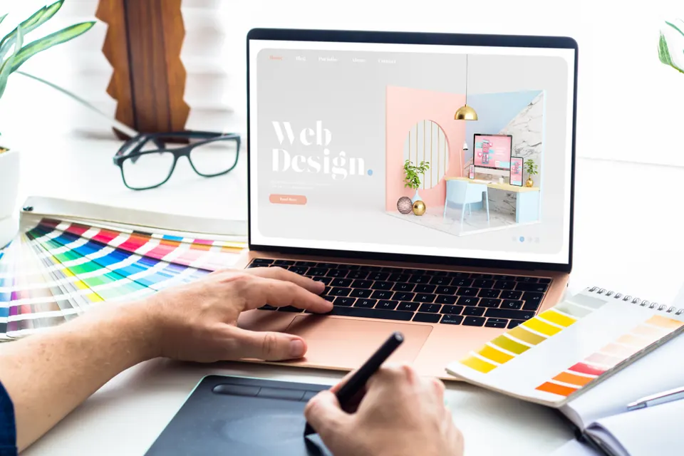Designer sketching a website layout beside color swatches